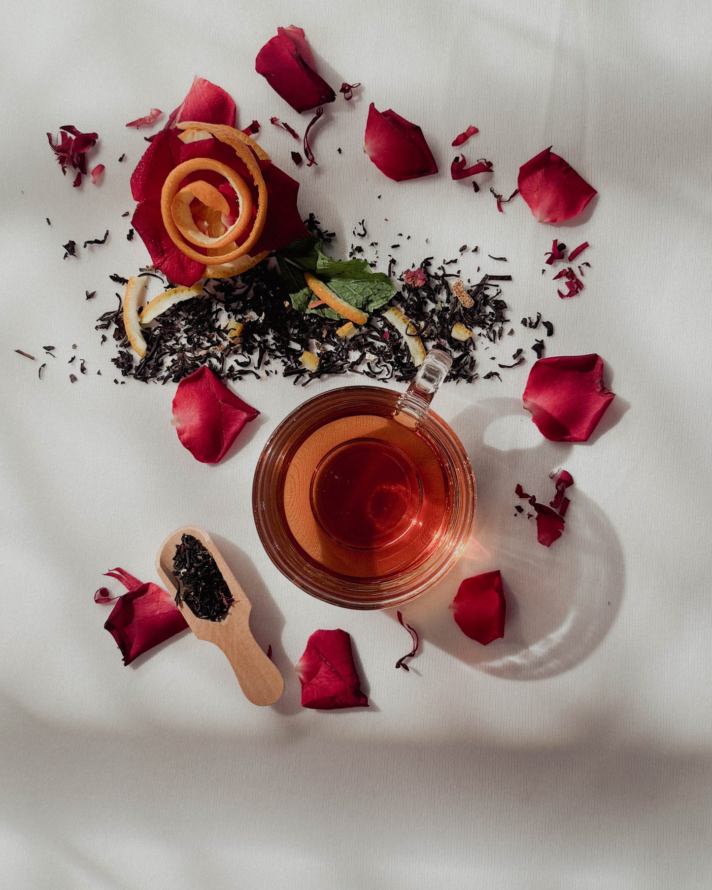 Tea cup with rose petals and tea leaves on a white surface
